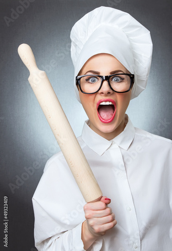 Photo: Mad chef woman cook with a rolling pin isolated on gray Mad chef woman cook with a rolling pin isolated on gray