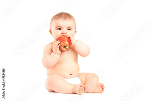 Photo: A 9 month old baby boy sitting and eating an apple A 9 month old baby boy sitting and eating an apple