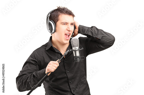 Photo: A male singer with headphones performing a song A male singer with headphones performing a song