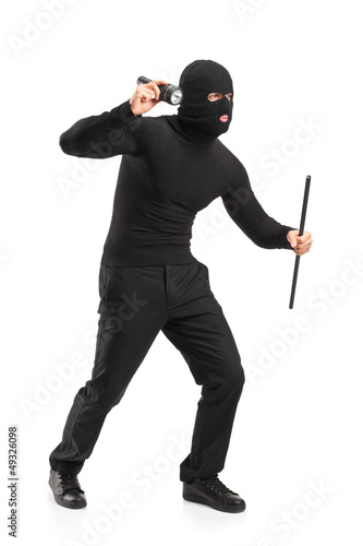 Photo: Full length portrait of a robber with mask holding a flashlight Full length portrait of a robber with mask holding a flashlight