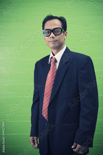 Photo: asian man in dark suit standing on green background asian man in dark suit standing on green background