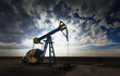 Operating oil well profiled on dramatic cloudy sky