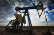 Operating oil well profiled on dramatic cloudy sky