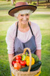 Smiling elderly woman carrying basket of vegetables