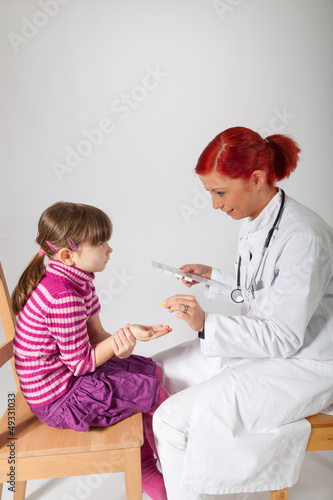 Photo: Die Kinderärztin gibt ihrer Patientin eine Tablette Die Kinderärztin gibt ihrer Patientin eine Tablette