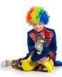 Boy clown with kitten inside hat over the white background