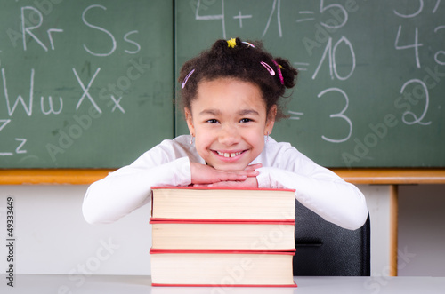 Photo: lächelndes kind stützt sich auf büchern ab lächelndes kind stützt sich auf büchern ab