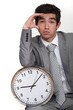 Business with clock suffering from headache