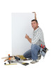 Carpenter posing by advertising panel
