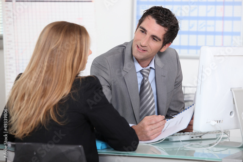 Photo: Man interviewing a young woman across a desk Man interviewing a young woman across a desk