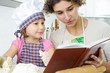 Young mother with little daughter preparing cookies
