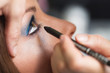 Visagistin trägt Eyeliner auf