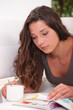 young woman enjoying peaceful moment skimming through catalogue
