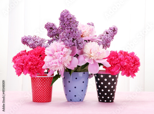 Photo: spring flowers in cups on table on white wooden background spring flowers in cups on table on white wooden background