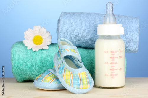 Photo: Baby bottle of milk with baby's bootees near towels Baby bottle of milk with baby's bootees near towels