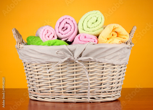 Photo: Colorful towels in basket on color background Colorful towels in basket on color background