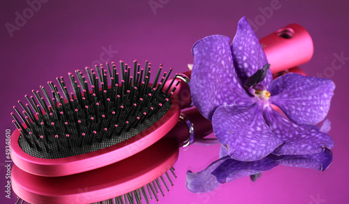 Photo: Comb brush and flower, on bright violet background Comb brush and flower, on bright violet background