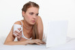Young woman laying on bed with laptop and coffee