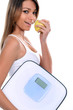 woman holding apple and bathroom scales
