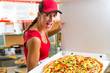 Photo: Woman holding a whole pizza in hand Woman holding a whole pizza in hand