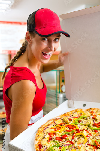 Photo: Woman holding a whole pizza in hand Woman holding a whole pizza in hand