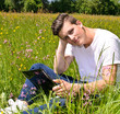 Photo: Junger Mann arbeitet mit Notebook auf Wiese Junger Mann arbeitet mit Notebook auf Wiese