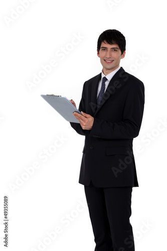 Photo: Businessman writing on his clipboard Businessman writing on his clipboard