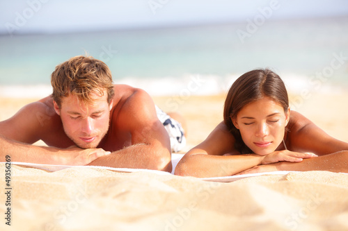 Photo: Young couple relaxing sleeping on beach Young couple relaxing sleeping on beach