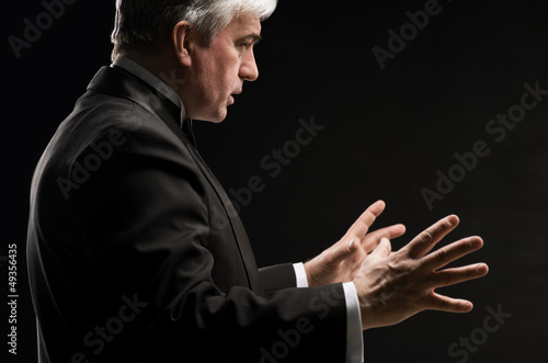 Photo: Closeup portrait of male orchestra conductor directing with his Closeup portrait of male orchestra conductor directing with his