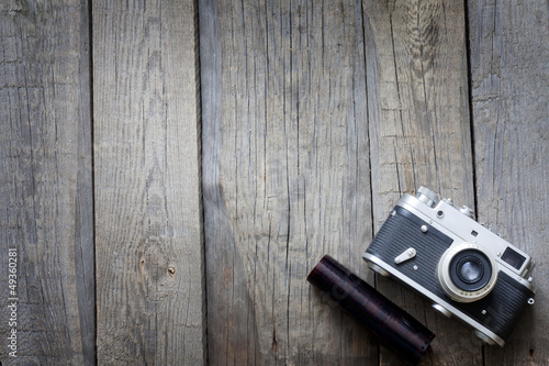 Photo: Old retro camera on vintage wooden boards abstract background Old retro camera on vintage wooden boards abstract background