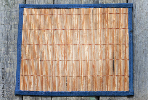Photo: Bamboo mat on vintage wooden boards food background concept Bamboo mat on vintage wooden boards food background concept