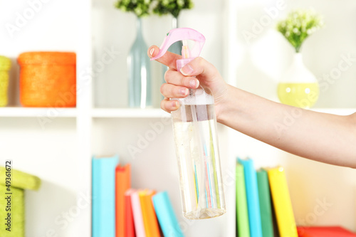 Photo: Sprayed air freshener in hand on white shelves background Sprayed air freshener in hand on white shelves background