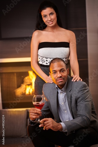 Photo: Attractive interracial couple at home by fireplace Attractive interracial couple at home by fireplace