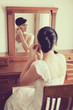 bride sitting on chair and looking through mirror