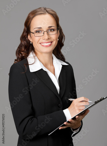 Photo: Smiling business woman with clipboard, on gray Smiling business woman with clipboard, on gray