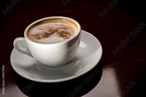 Photo: White cup of freshly brewed coffee in cafeteria White cup of freshly brewed coffee in cafeteria