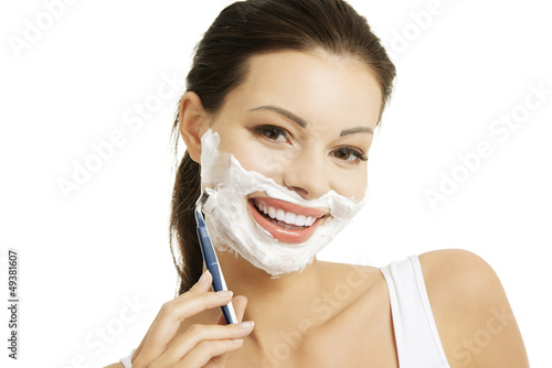 Photo: Beautiful woman shaving her face with a razor Beautiful woman shaving her face with a razor