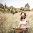 Photo: Young woman in lotus position in a sunny field Young woman in lotus position in a sunny field