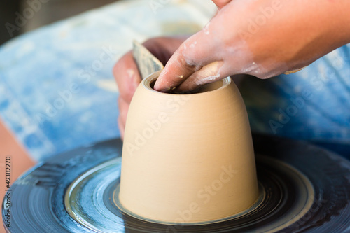 Photo: Potter creating clay bowl on turning wheel Potter creating clay bowl on turning wheel
