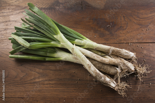 Photo: Bunch of calçots on wooden table Bunch of calçots on wooden table