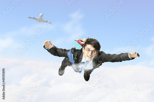 Photo: Young businessman flying with parachute on back Young businessman flying with parachute on back