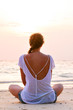 woman is sitting on beach at sunrise