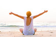 woman is sitting on beach at sunrise
