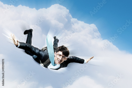 Photo: Young businessman flying with parachute on back Young businessman flying with parachute on back