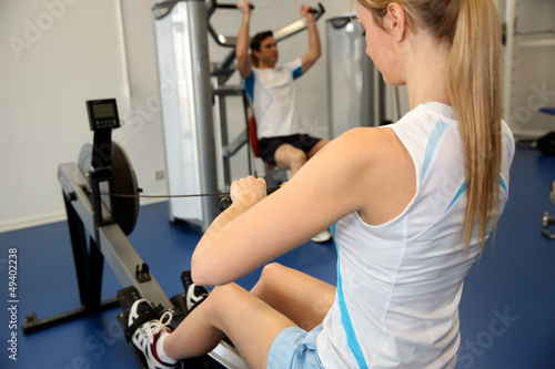 Photo: Woman using rowing equipment in gym center Woman using rowing equipment in gym center