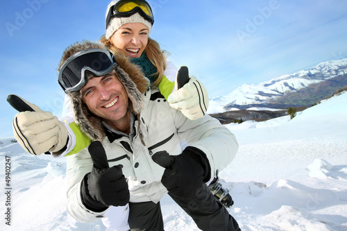 Photo: Cheerful snowboarder holding girlfriend on his back Cheerful snowboarder holding girlfriend on his back