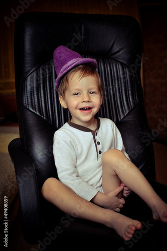 Photo: little boy in a purple hat and barefoot fun sitting on a chair little boy in a purple hat and barefoot fun sitting on a chair