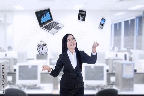 Photo: Multitasker businesswoman using laptop, calculator, phone, clock Multitasker businesswoman using laptop, calculator, phone, clock