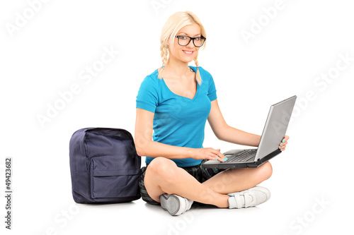 Photo: A smiling blond student sitting on a floor and working on a lapt A smiling blond student sitting on a floor and working on a lapt