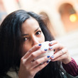 Young woman drinking coffee in a cafe outdoors. 